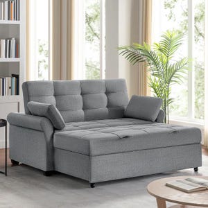 A gray Serta convertible sleeper sofa with a tufted cushion design, adjustable backrest, and one armrest cushion is positioned in a bright room beside a plant.