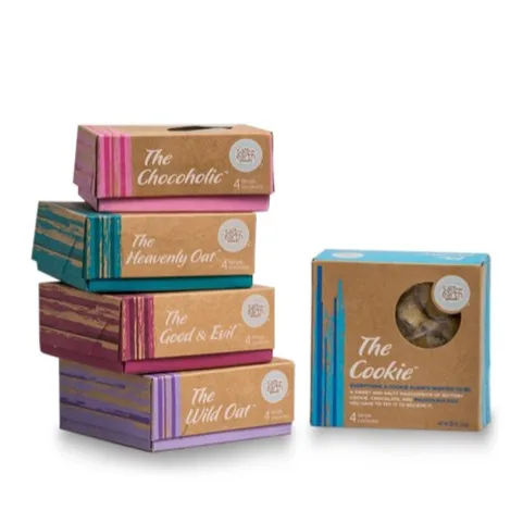 Stack of four cookie boxes labeled \“The Chocoholic,\“ \“The Heavenly Oat,\“ \“The Good & Evil,\“ \“The Wild Oat,\“ alongside a separate box labeled \“The Cookie,\“ each containing 4 cookies.