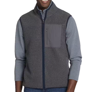 A man is wearing a gray sherpa fleece vest with a zippered front and a contrasting chest pocket over a long-sleeve gray shirt.