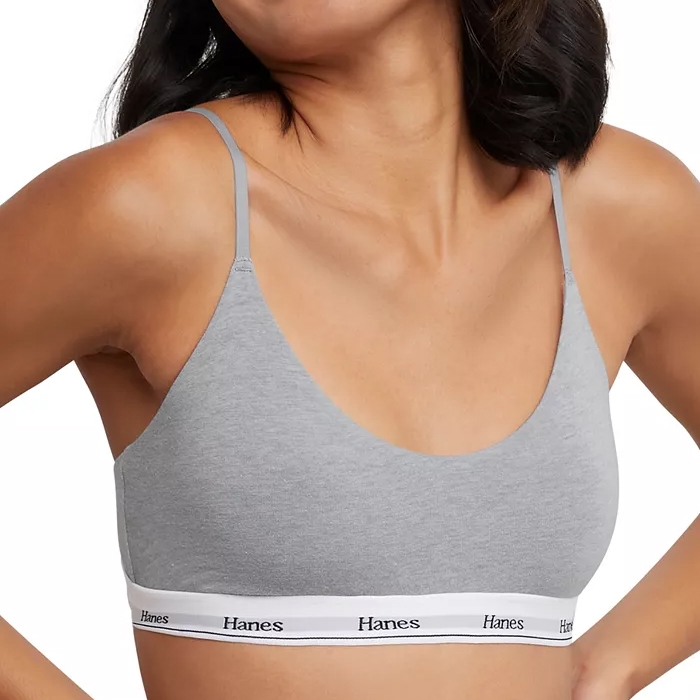 A woman is wearing a gray Hanes bralette with thin straps and a white elastic band featuring the brand's logo.