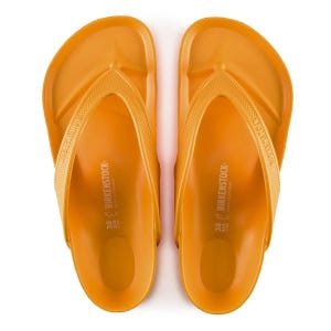 A pair of orange Birkenstock flip-flops with the brand's name embossed on the straps and footbed.