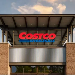 Costco Wholesale store entrance with large, prominent signage displaying the company name in red and blue against a metal and brick facade.