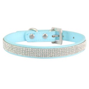 Light blue collar adorned with several rows of sparkling rhinestones and featuring a metal buckle for fastening.