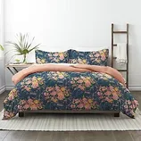 Floral patterned bedding set with pink sheets on a bed, accompanied by matching pillowcases.