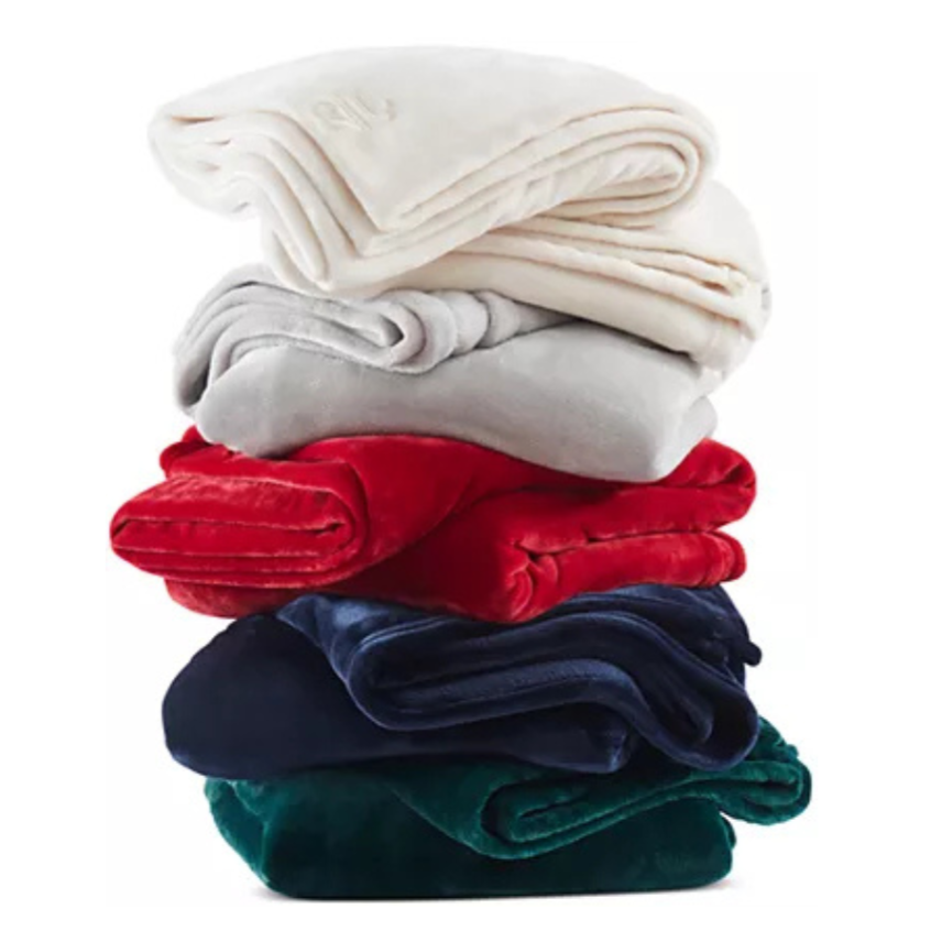 A stack of folded blankets in various colors: white, gray, red, navy blue, and green.