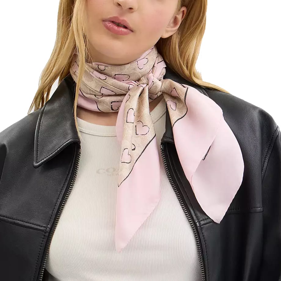 A woman wearing a black leather jacket and a light pink patterned scarf with heart designs, paired with a white ribbed top.