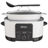Ninja slow cooker and multi-cooker with a control panel featuring modes for slow cook, sear/sauté, steam, keep warm, sous vide, braise, bake, and proof. Includes a glass lid and a slotted spoon.