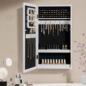 A wall-mounted jewelry organizer cabinet with open doors, displaying various necklaces, earrings, and shelves for cosmetics.