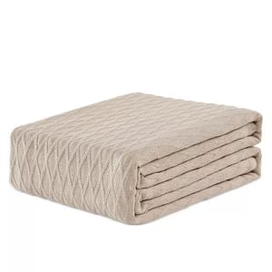 A folded beige blanket with a diamond knit pattern.