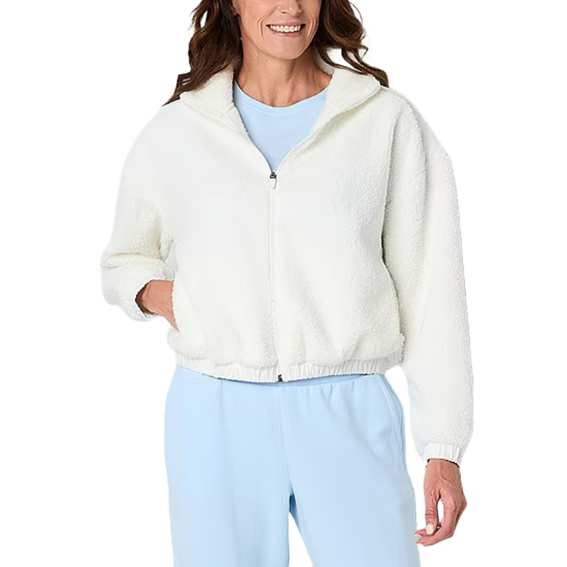 A woman wearing a white zip-up sherpa jacket over a light blue top, paired with light blue pants.