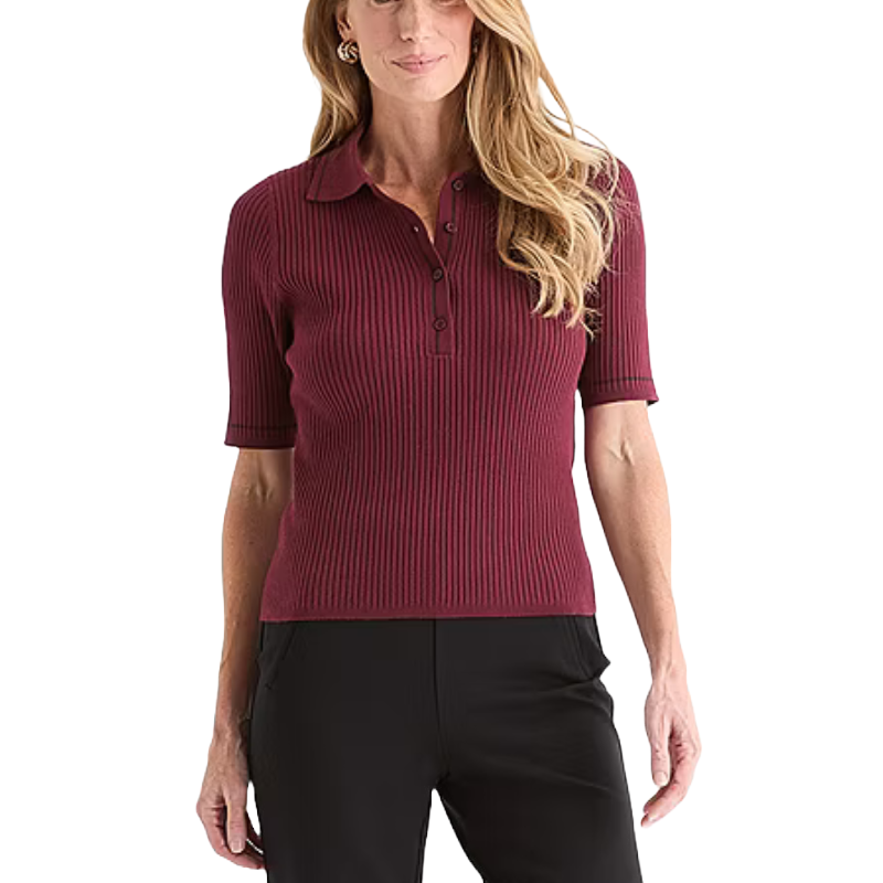 A woman is wearing a short-sleeved, ribbed burgundy polo shirt paired with black pants.