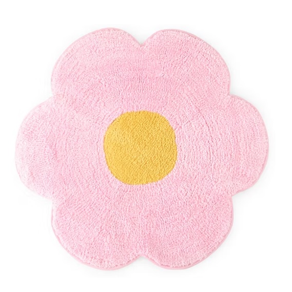 A pink, flower-shaped rug featuring a yellow center, crafted from a plush, textured material.