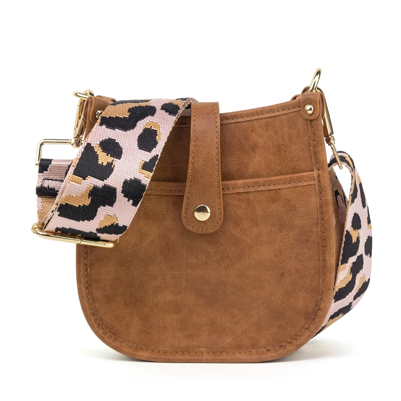 Brown faux-leather crossbody bag with a decorative button and a detachable, wide strap featuring a leopard print pattern in pink, black, and tan. Gold-tone hardware completes the design.