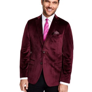 A man wears a wine-colored velvet blazer with a white dress shirt and a pink tie.