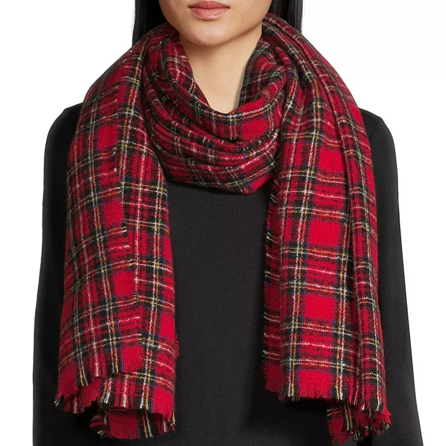 A red plaid scarf with fringed edges is worn over a black top.