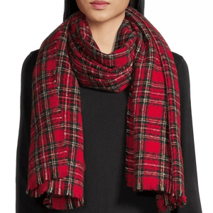 A red plaid scarf with fringed edges is worn over a black top.