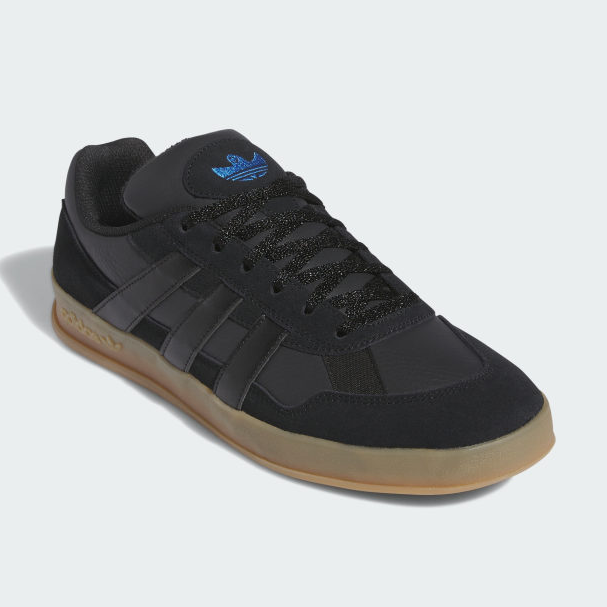 A black sneaker with a gumsole and three stripes on the side.