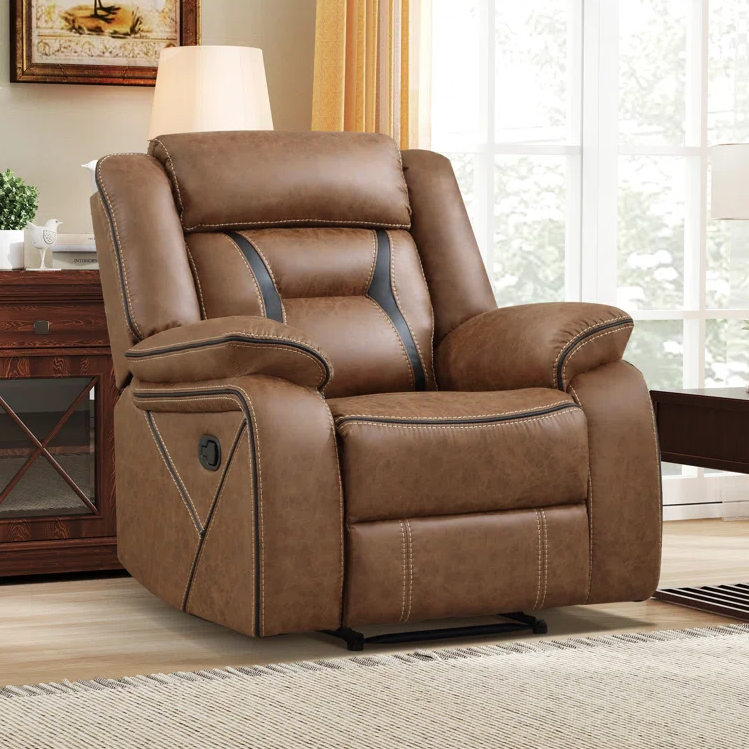 A brown reclining armchair with black accents and visible stitching is positioned near a side table with a lamp in a cozy living room setting.