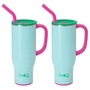 Two light blue insulated mugs with pink handles, green lids, and pink straws. The brand name \“swig\“ appears on each mug.