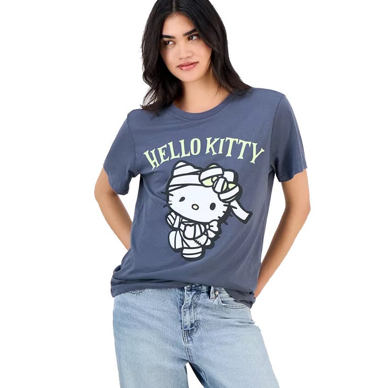 A woman is wearing a gray T-shirt with a \“Hello Kitty\“ design featuring the character dressed as a mummy, paired with light blue jeans.