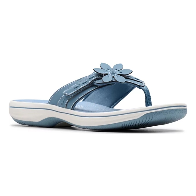 A blue thong sandal with white stitching features a flower embellishment on the strap, a cushioned sole, and a slight platform, designed for comfort.