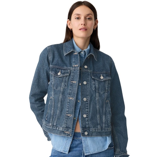 A woman wearing a denim jacket with button closures and chest pockets.