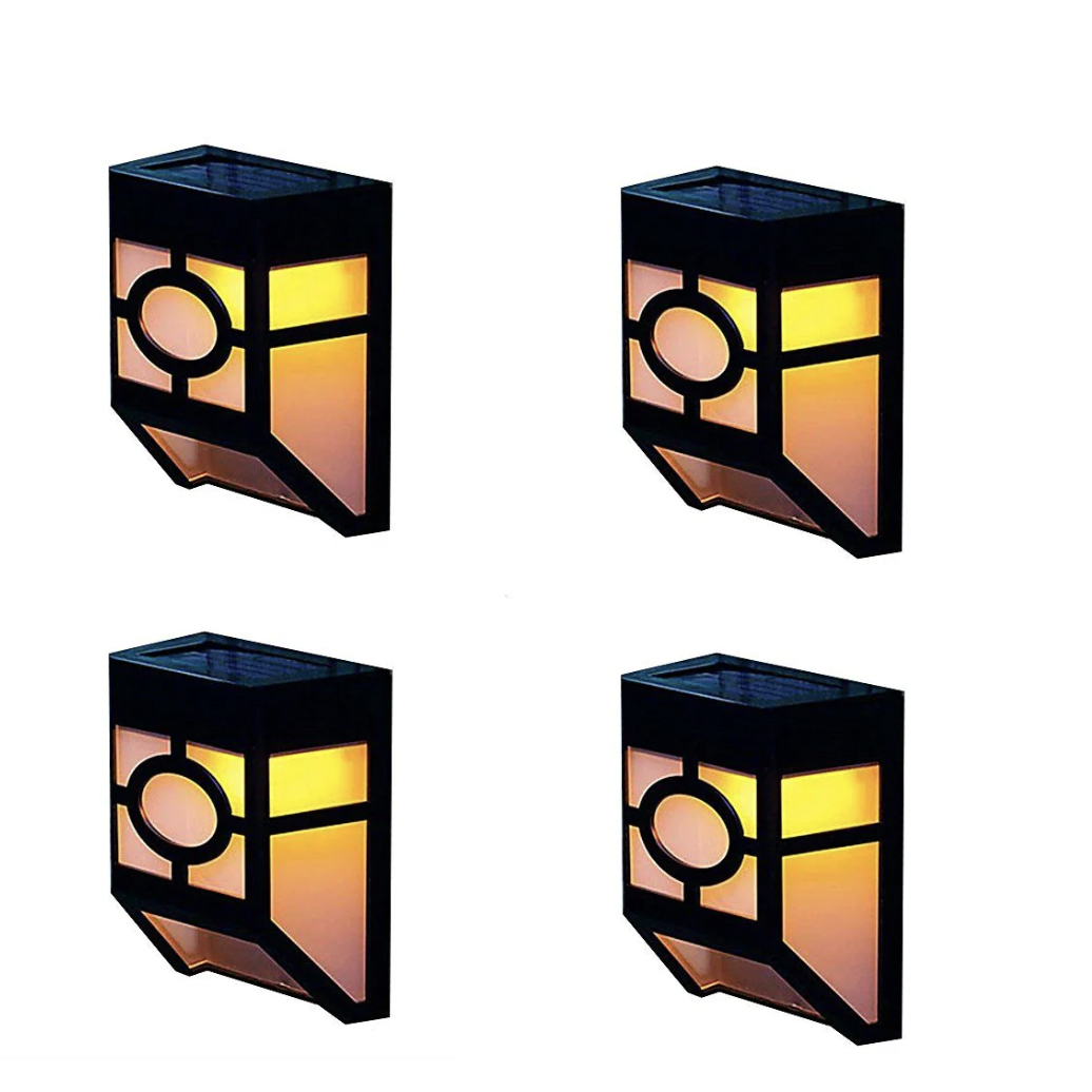 Four LED solar-powered lights designed to attach to a fence display a warm glow through an orange and yellow pane with a circular pattern on the lower section.