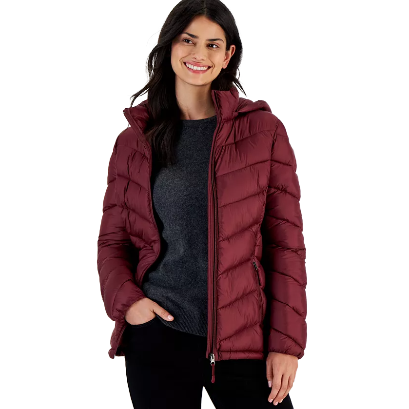 Woman wearing a burgundy puffer jacket with a hood, dark gray sweater, and black pants.