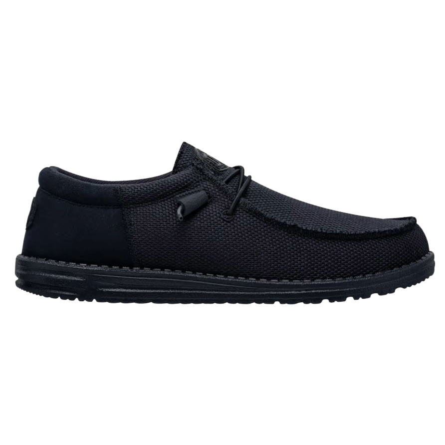 A black slip-on shoe with a textured fabric exterior and a low-profile rubber sole, featuring simple lace detailing.