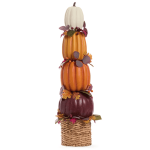 A stacked pumpkin decoration featuring a white, two orange, and a dark purple pumpkin, accented with fall foliage, all set in a woven basket.
