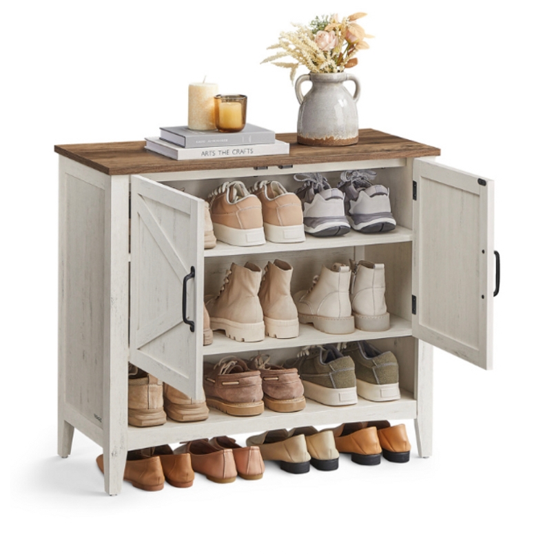 A shoe storage cabinet with a rustic wood finish features multiple shelves, accommodating various footwear. The top is decorated with books, candles, and a decorative vase with flowers.