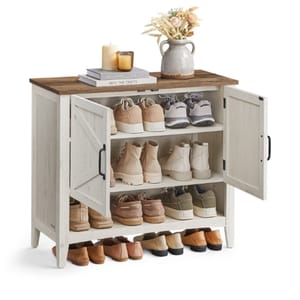 A shoe storage cabinet with a rustic wood finish features multiple shelves, accommodating various footwear. The top is decorated with books, candles, and a decorative vase with flowers.