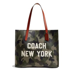 Coach New York tote bag with a camouflage pattern and brown leather handles, featuring prominent white text and a leather tag.