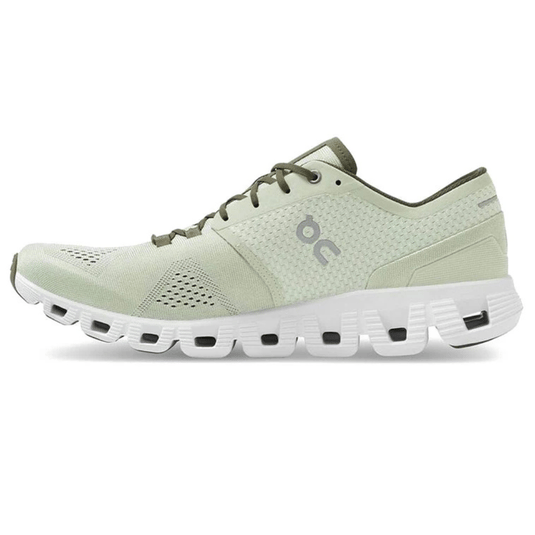 Light green athletic shoe featuring a perforated upper and a white, cushioned sole with distinctive cut-out patterns. The shoe has a logo on the side and lace-up design for closure.