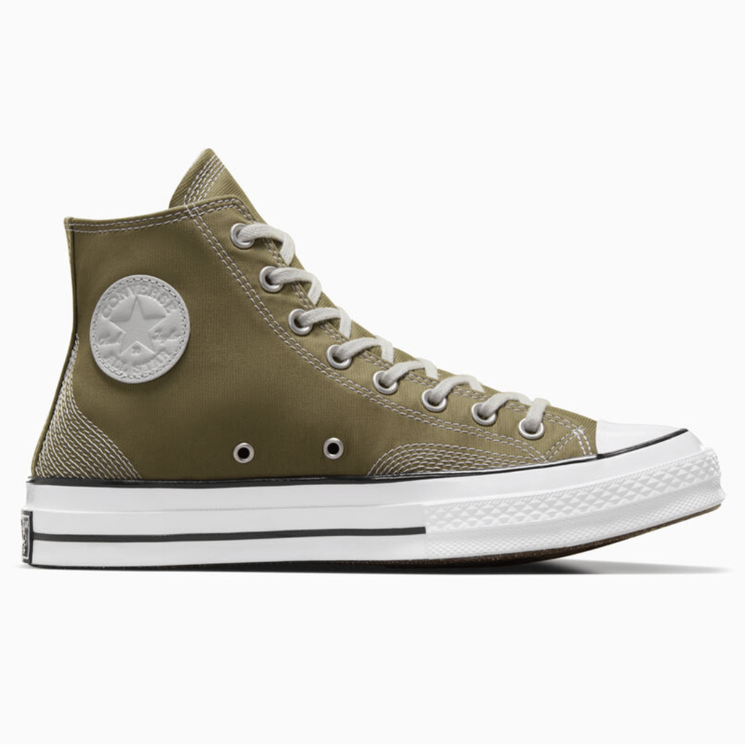 Olive green high-top canvas sneaker with a white rubber toe cap, white laces, and a circular logo patch on the side.