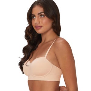 A woman is wearing a beige balconette bra with thin straps and a seamless design, offering support and a smooth look.