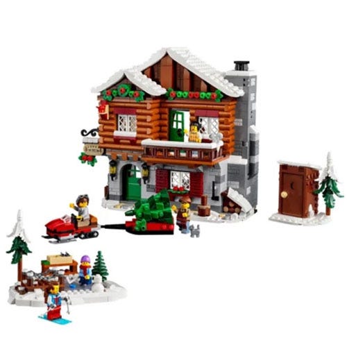A winter-themed LEGO set featuring a detailed log cabin with snowy accents, a pine tree, an outdoor scene with figures skiing and sledding, and small accessories like trees and animals.