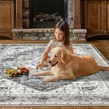 A child and a golden retriever are on a patterned rug, with toy construction vehicles in front of them, set against a backdrop of a stone fireplace and wooden cabinets.