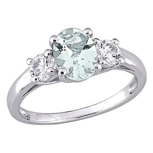 A silver ring featuring an oval-shaped pale green gemstone flanked by two round clear stones in a three-stone setting.