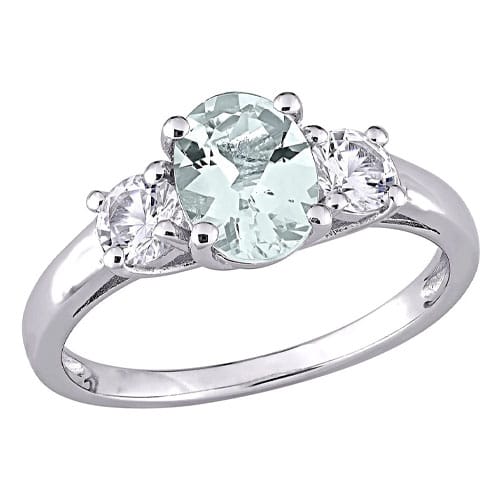 A silver ring featuring an oval-shaped pale green gemstone flanked by two round clear stones in a three-stone setting.