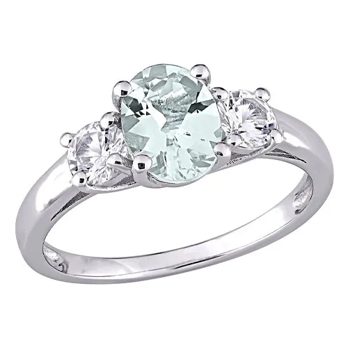 A silver ring featuring an oval-shaped pale green gemstone flanked by two round clear stones in a three-stone setting.