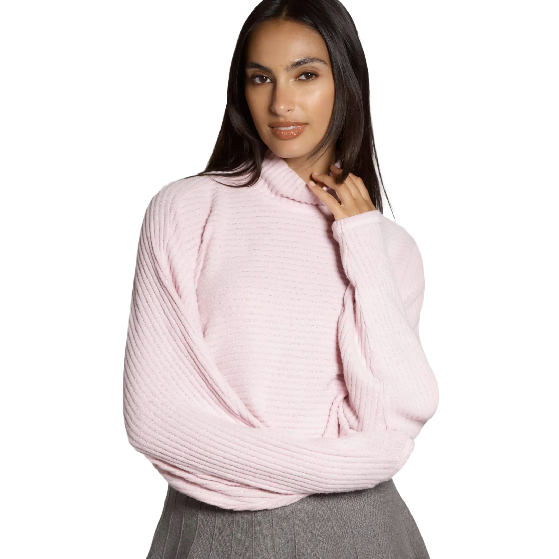 A woman is wearing a light pink, ribbed turtleneck sweater with batwing sleeves, paired with a gray pleated skirt.