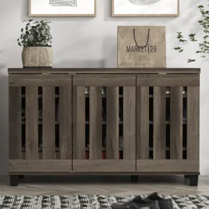 Brown wooden shoe cabinet with slatted doors, topped with a potted plant and a shopping bag labeled \“Market 29\“. Two abstract framed artworks hang above, and there's a patterned rug and shoes on the floor in front.