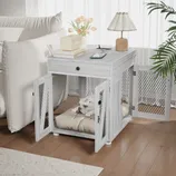 A dual-purpose end table doubles as a dog crate with mesh doors, housing a dog on a cushion. The top surface holds a lamp, books, a speaker, and a phone.