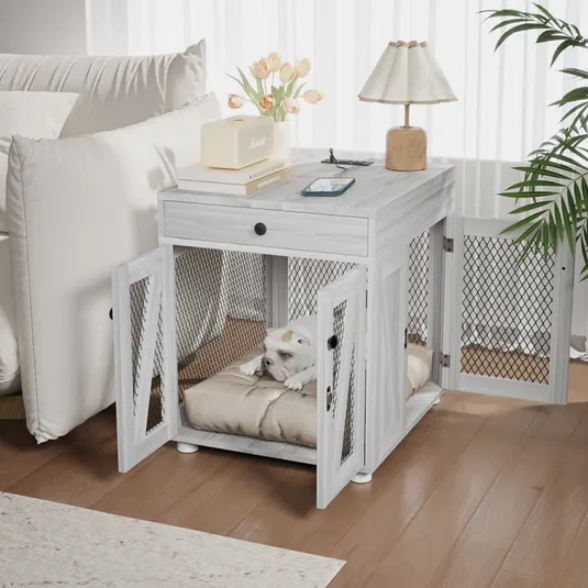 A dual-purpose end table doubles as a dog crate with mesh doors, housing a dog on a cushion. The top surface holds a lamp, books, a speaker, and a phone.