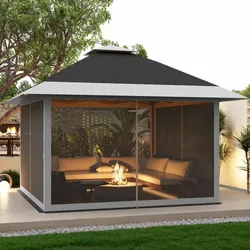 A gazebo with a gray and black roof encloses a cozy seating area with plush cushions around a small fire pit.