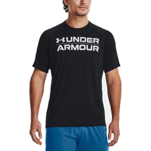 A man is wearing a black Under Armour T-shirt with white lettering, paired with blue shorts.