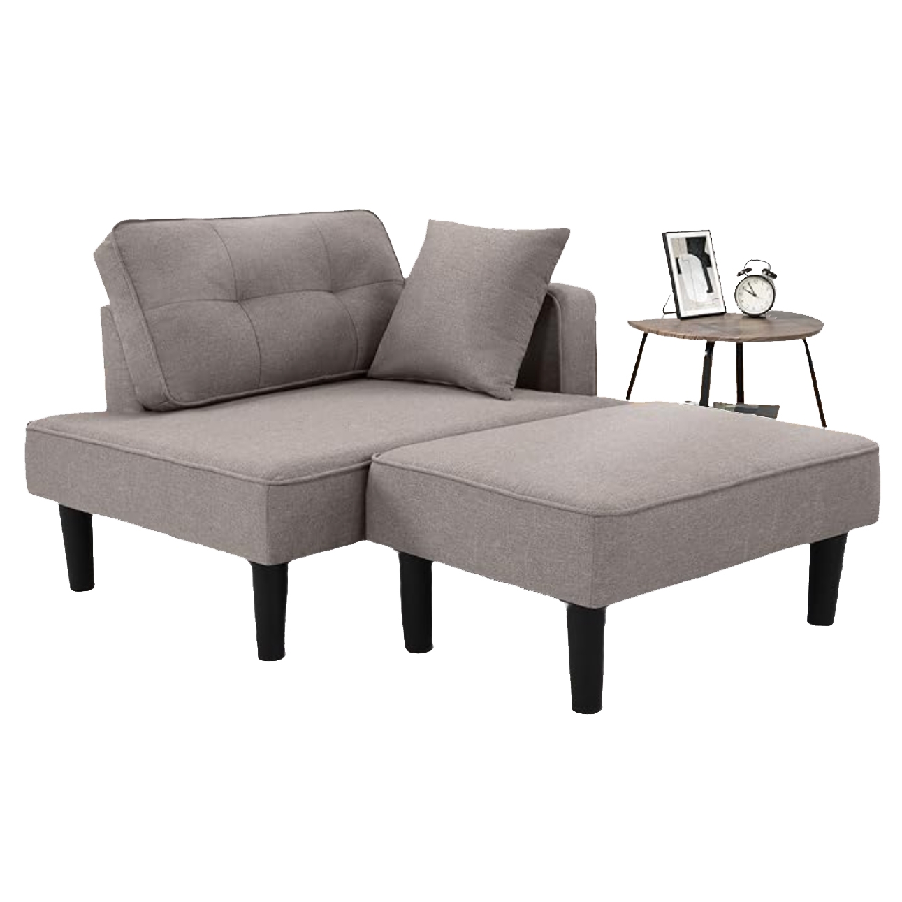 A modular, light gray fabric recliner sofa with a detachable ottoman and black legs, accompanied by a matching pillow. A small round side table with an alarm clock and picture frame is positioned nearby.