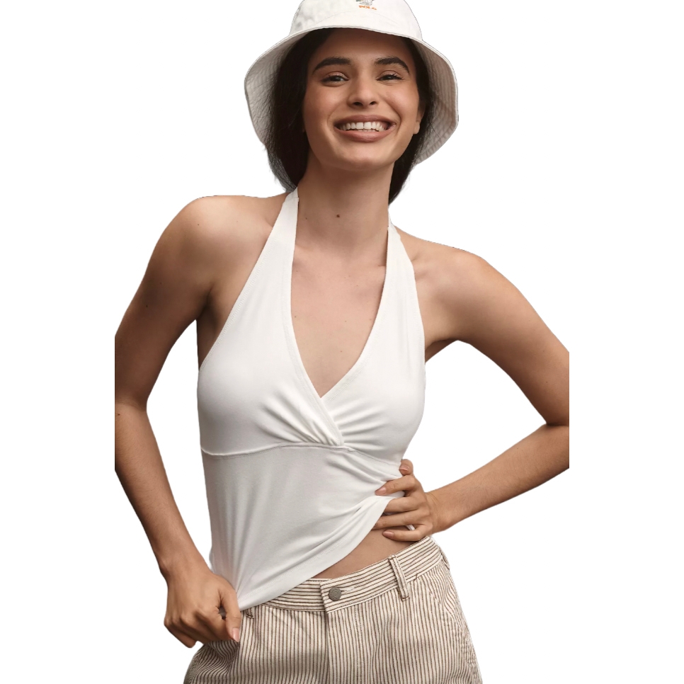 A smiling person is wearing a white halter top, beige pinstriped pants, and a white bucket hat.