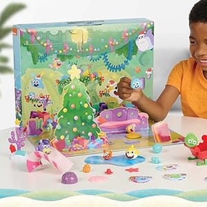 A child is playing with a colorful board game featuring a Christmas tree and various whimsical characters.